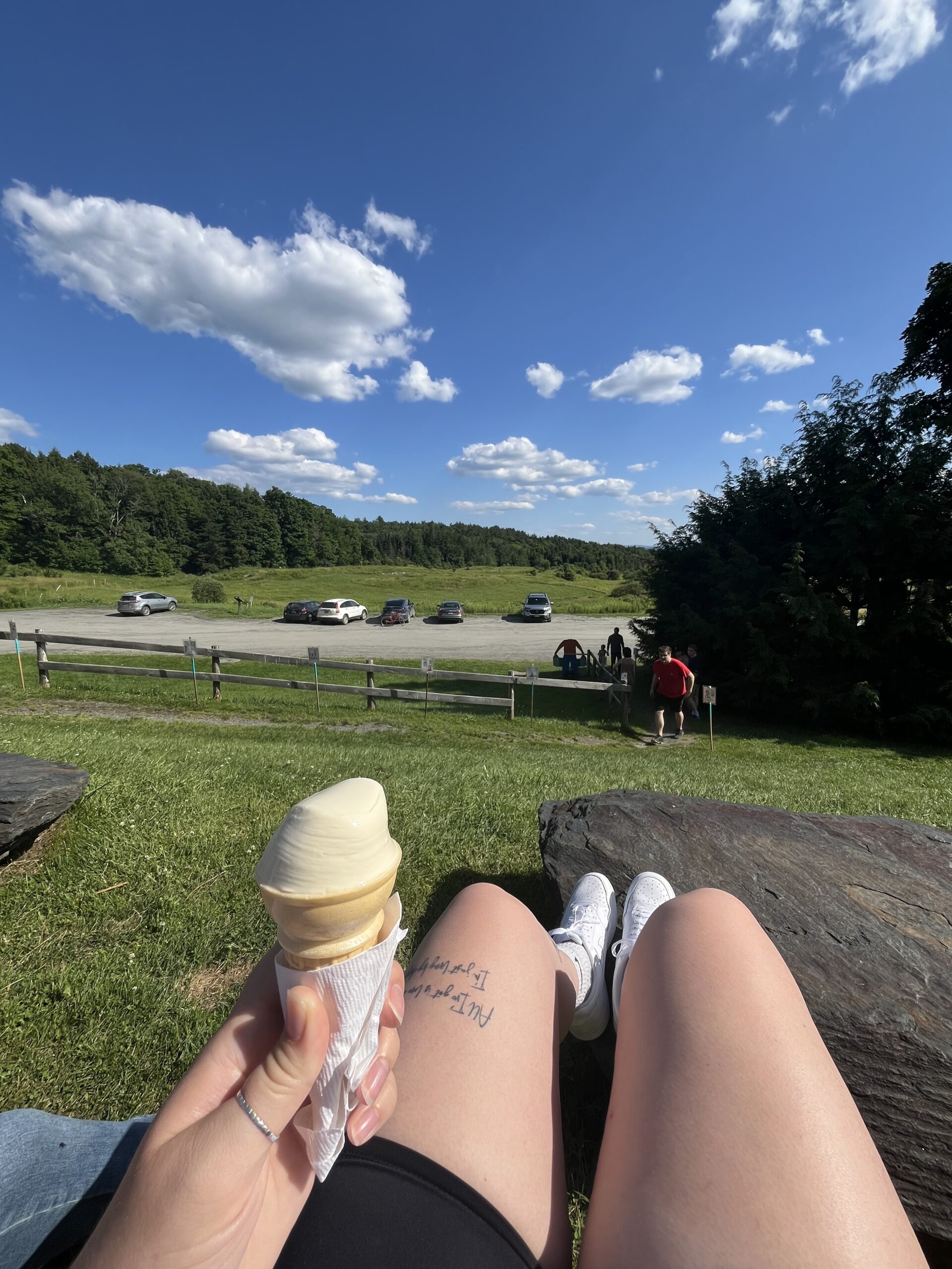 Picture shows Jenna's knees while eating a maple creemee at Morse Family Maple Farms in Vermont. Background shows beautiful mountain landscape. 