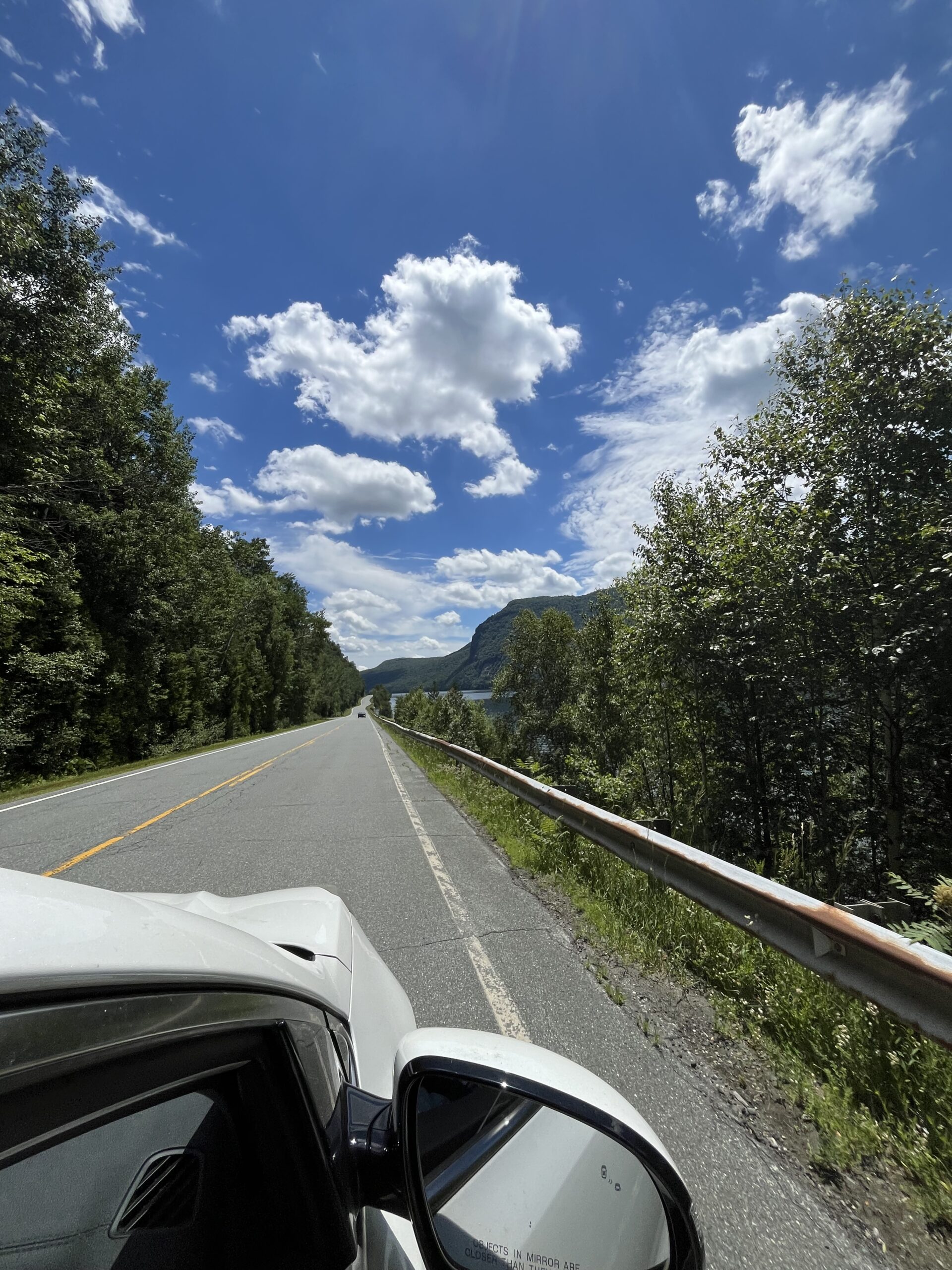 beautiful blue sky with clouds on the road in vermont. picture taken out the car window